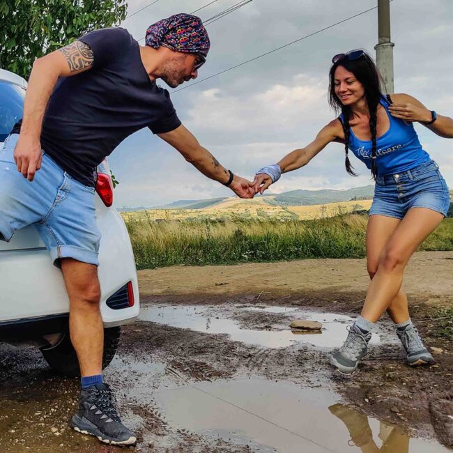 A couple hand in hand near a car with puddles on the ground