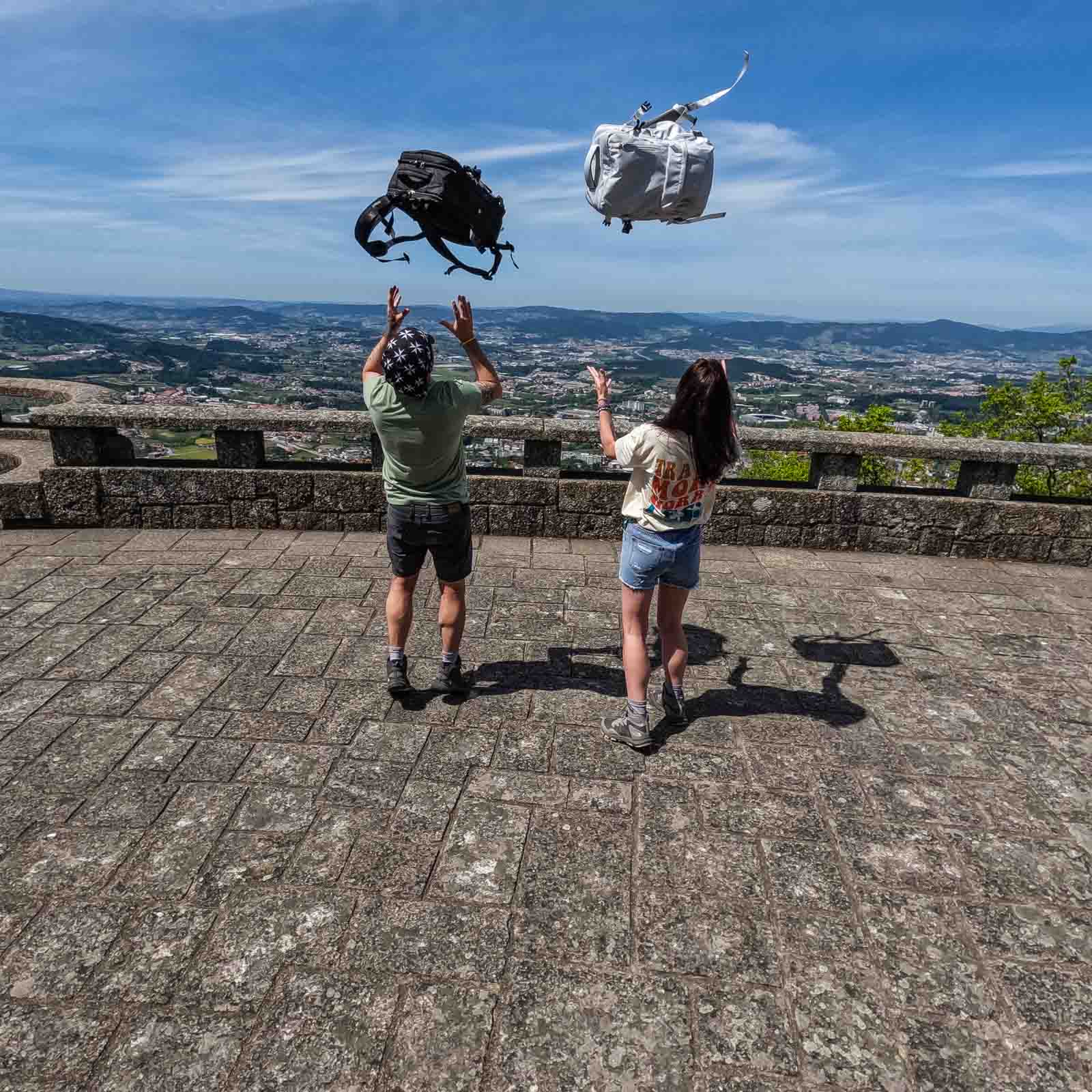 Couple throwing backpacks in the air - Portugal Travel Guide
